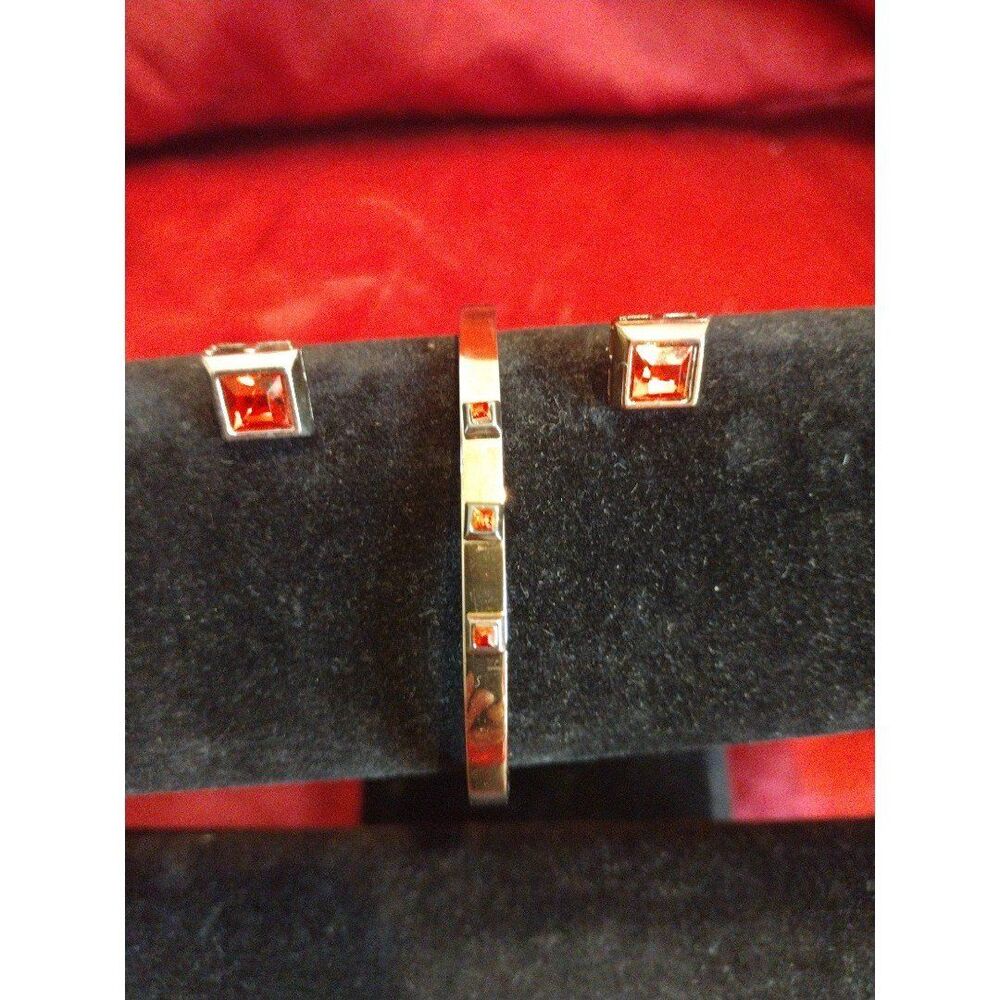 Gold tone bangle bracelet and matching earrings with simulated garnet accents